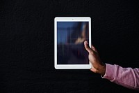 Hand holding a digital tablet on black background