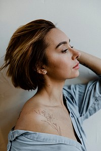 Portrait of a short haired woman with a floral tattoo on her shoulder 