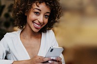 Cheerful black woman using her phone in a house