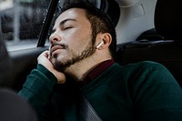 Man asleep in a car wearing wireless earphones