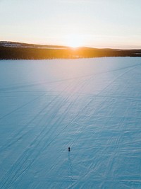 Man walking on the snow while admiring the sunset