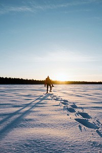 Woman trekking through the snow at sunrise