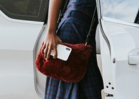 Black woman holding her phone while getting into a car