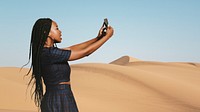 Black woman taking a photo on a desert