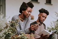 Black couple reading a book and playing on the phone