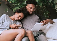 Black couple reading and playing on the phone in the garden
