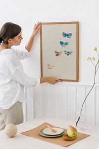 Woman hanging a photo frame on a white wall
