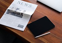 Newspaper on a table with a digital tablet