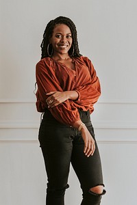Happy empowering black woman standing by a white wall