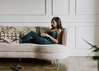 Casual woman working on her laptop while laying on the couch