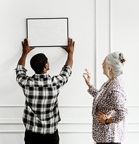 Black man hanging floral art frame on the wall