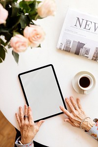 Old woman using a digital tablet in a cafe