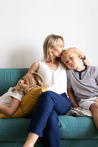Blonde mom kissing her son&rsquo;s head and relaxing with daughter on the couch 