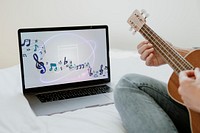 Woman using a laptop screen mockup while playing ukulele during quarantine 