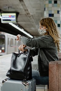 Woman looking at her watch while waiting for the train during the coronavirus pandemic 