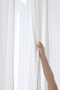 Hand opening a white curtain