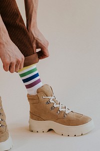 Man folding up pant leg with suede sneaker