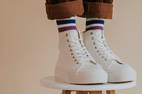 Man in white high top shoes standing on chair