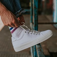 Man tying laces on white sneaker