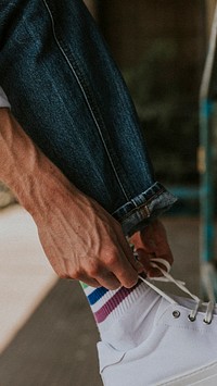 Man fixing shoelaces on white sneaker mobile phone wallpaper