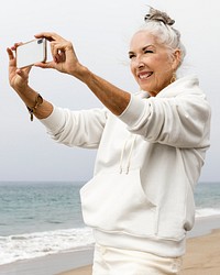 Mature woman taking a photo at the beach in winter