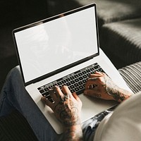 Tattooed man working on laptop screen mockup