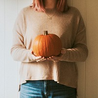 Woman holding Halloween pumpkin in a farmhouse