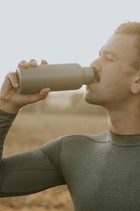 Man drinking water from stainless steel bottle after working out