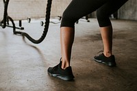 Sportive woman doing a battle rope in a gym