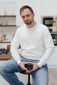 Happy man sitting on a stool with a camera