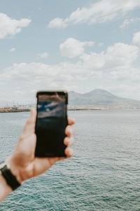 Man using his smartphone to capture the scenic ocean