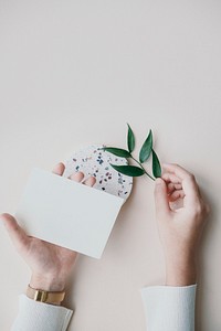 Woman holding a blank card with Ruscus leaves