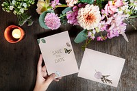 Woman holding a save the date card by a bouquet of flowers