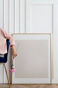 Woman holding a flower sitting by a frame