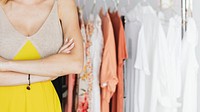 Woman crossing her arm and smiling happily in front of a garment rack