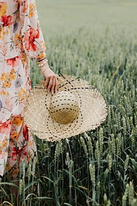 Woman in a floral dress with a woven hat in a field