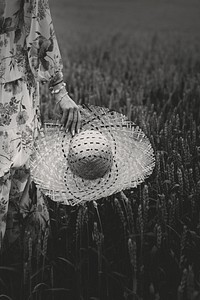 Woman in a floral dress with a woven hat in a field