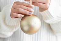 Woman in a white sweater holding a gold bauble