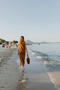 Girl in a brown dress walking alone the beach