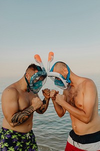 Men with full face snorkel mask standing against each other at the beach
