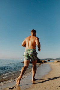 Rearview of man jogging along the beach