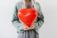 Woman showing a heart red balloon