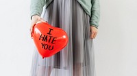Woman showing a red heart balloon with I Hate You on it