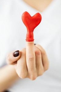 Red heart balloon on a middle finger