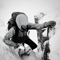 Mountaineer using an ice axe to climb Forcan Ridge in Glen Shiel, Scotland