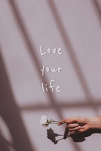 Love your life quote on a hand holding flower background
