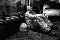 Firefighter sitting against wall, April 18, 2019, Cheshire, UK. Original public domain image from Flickr