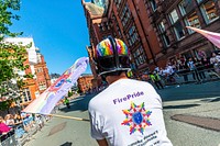 Man holding flag in parade, August 24, 2019, Manchester, UK. Original public domain image from Flickr