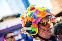 Man wearing colorful helmet in pride parade, August 24, 2019, Manchester, UK. Original public domain image from Flickr