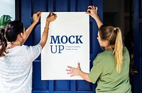 Women putting up a poster mockup